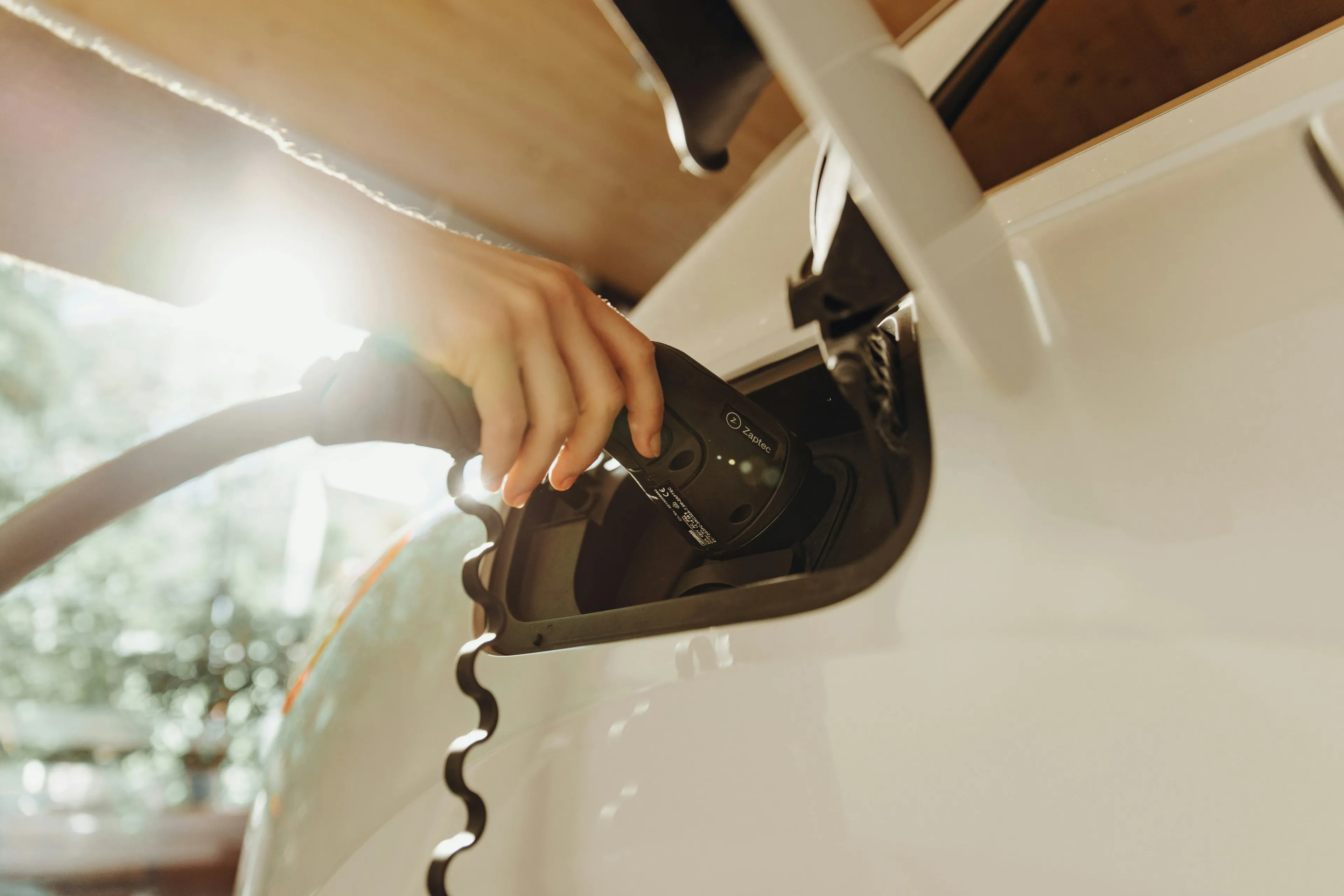 Pessoa conectando o carregador a um carro elétrico